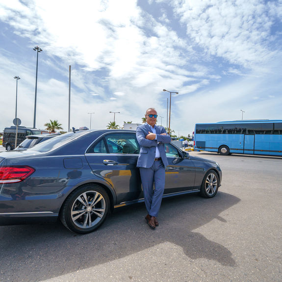 Professional taxi driver standing next to his car at the airport, ready for pickup service
